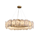 The Solvane LED Small Petal Alabaster Chandelier in Soft White & Brass features frosted, Spanish alabaster-inspired glass panels arranged like petals on a circular brass frame, suspended by thin cables from a round ceiling mount.