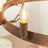 Close-up of the Bevgrove 12 Light Pendant's aged metal ring frame with a lit candle-style E14 bulb in a cylindrical holder.