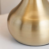 Close-up of the Endon Chartbury LED table lamp base, showing its curved brushed brass metal form against a pale background.