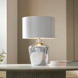 Danefield Table Lamp in chrome and cream, glass base with marbled effect, cream drum fabric shade, lit E27 bulb, shown on a table in a living room.