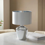 Danefield Table Lamp with mirrored chrome glass base and cream fabric drum shade, styled on a marble table in a neutral living room setting.