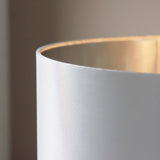 Close-up of the Danefield Table Lamp's cream fabric shade edge, showing woven texture and warm glow from the E27 bulb inside.