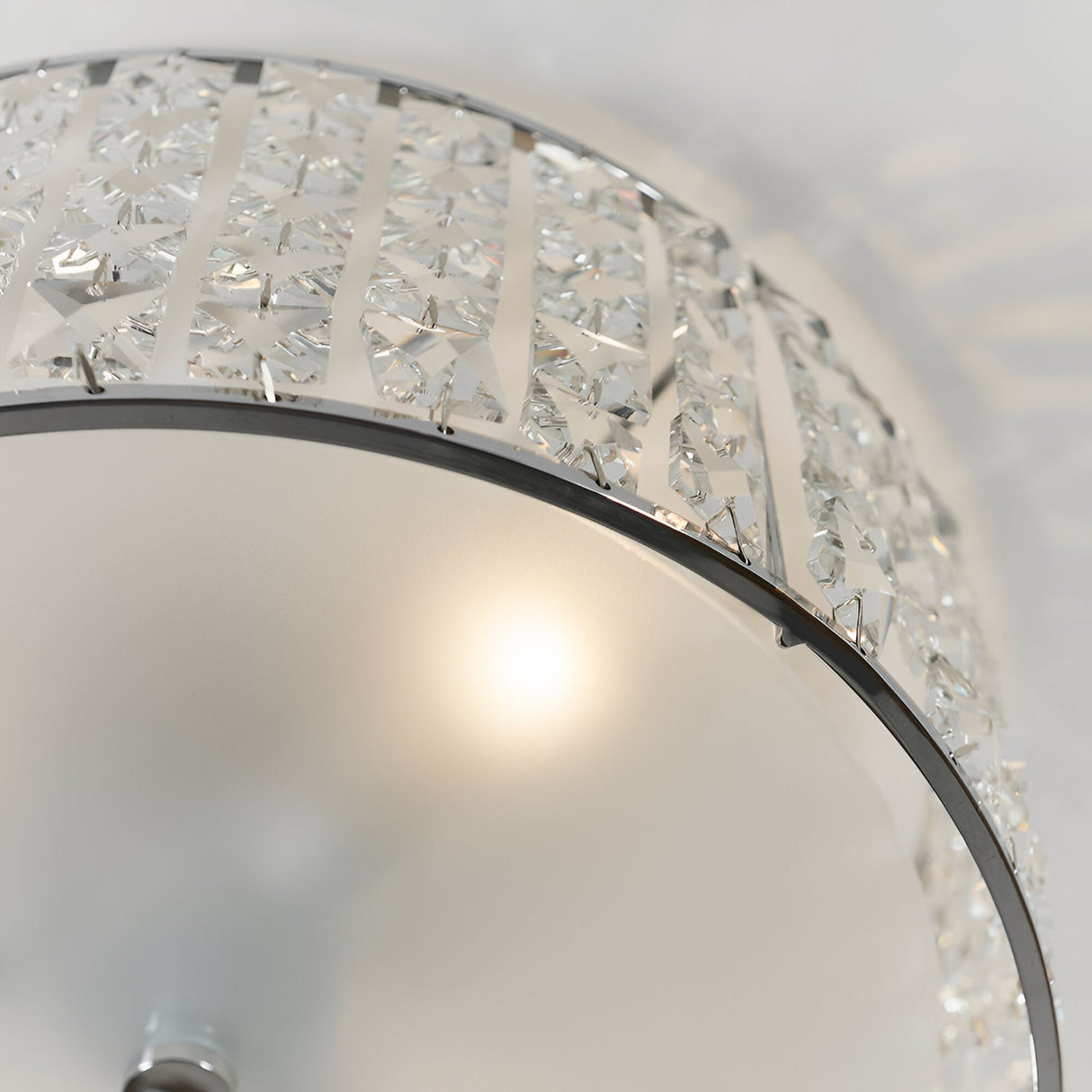 Close-up of Endon Ophelia flush bathroom ceiling light showing illuminated bulb behind frosted glass diffuser, chrome frame and crystal detailing.