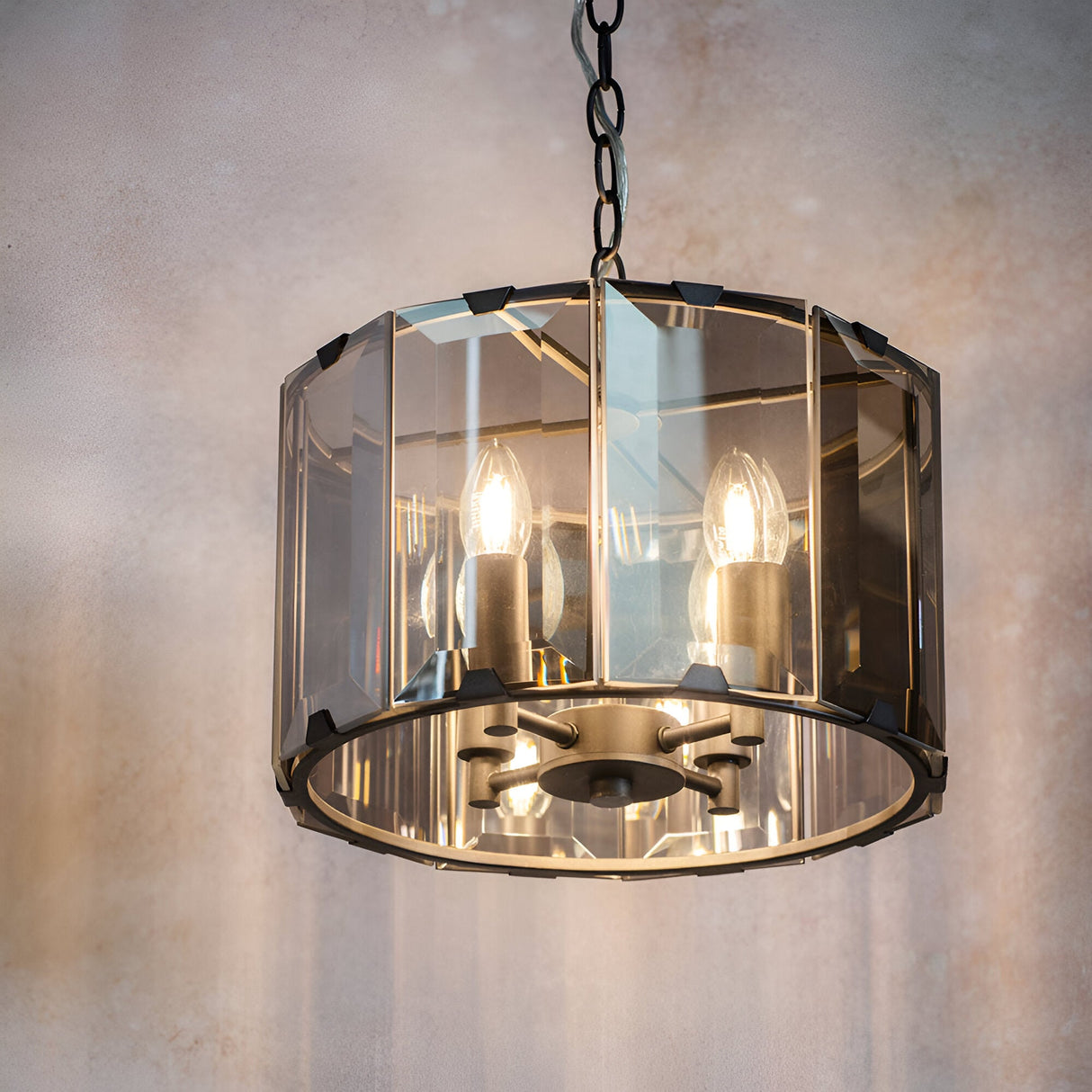 Bevshaw 4-light pendant in slate grey with a drum frame, bevelled smoke glass panels, exposed candle bulbs, and a chain hang.