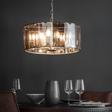 Endon Bevshaw 8 light pendant with bevelled smoke glass panels and slate grey frame, lit above a dining table set with wine glasses against a dark wall.