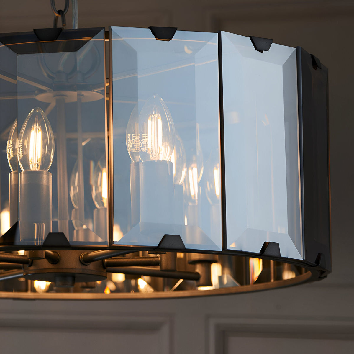 Close-up of Endon Bevshaw 8 light pendant showing bevelled smoke glass panels on a slate grey frame with lit E14 filament candle bulbs inside.