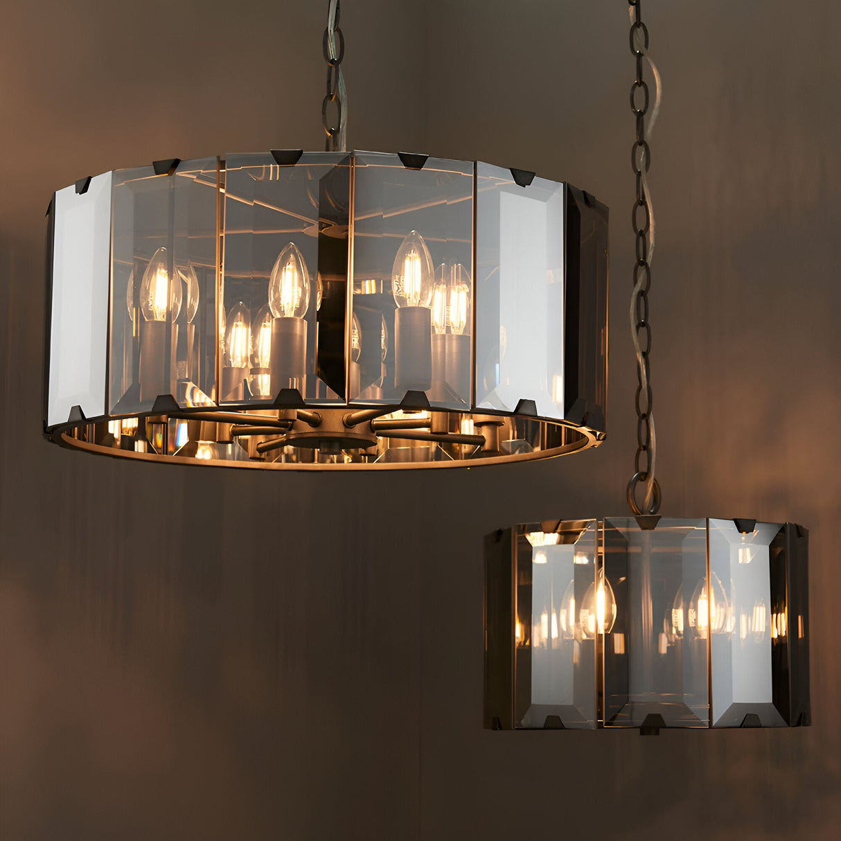 Endon Bevshaw 8 light pendant in slate grey with bevelled smoke glass panels and lit candle bulbs, shown alongside a smaller matching pendant on chains.