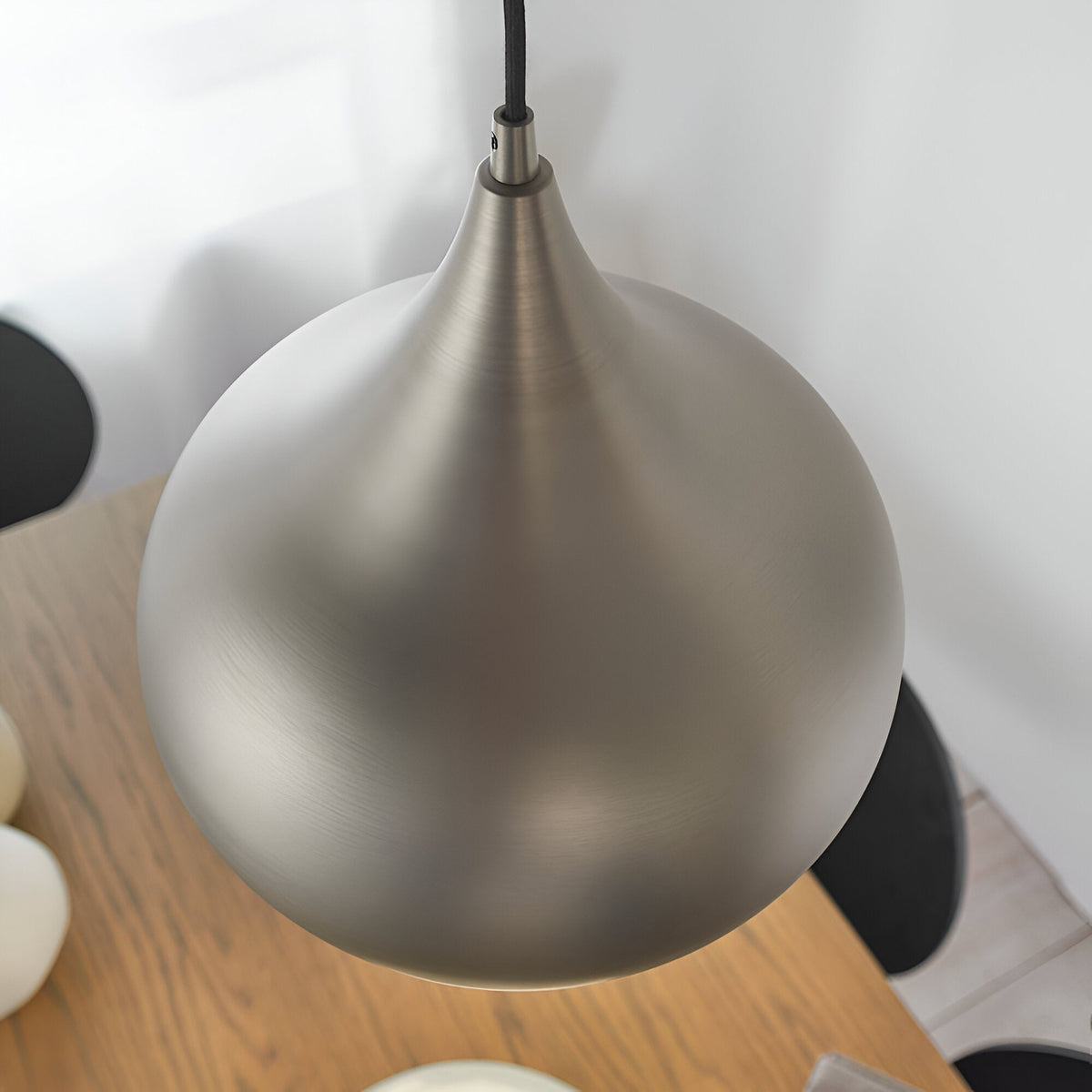 Ashleigh Pendant in matt nickel, teardrop-shaped metal shade with tapered neck, hung above a wood table in a dining setting.
