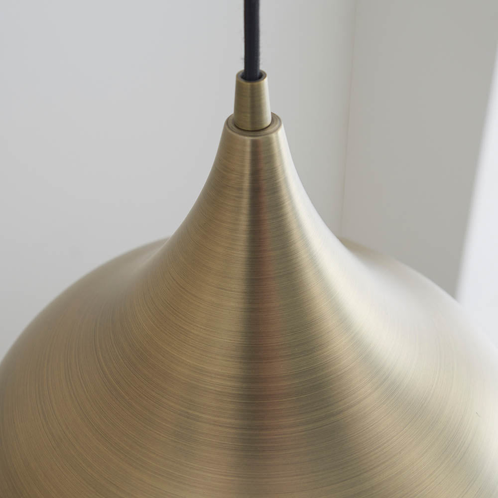 Close-up of the Endon Ashleigh pendant light showing its curved brass shade with brushed matt finish and black fabric flex against a white background.
