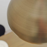 Close-up of the Endon Ashleigh pendant's spherical brass diffuser, showing the brushed matt antique brass finish against a pale wall.