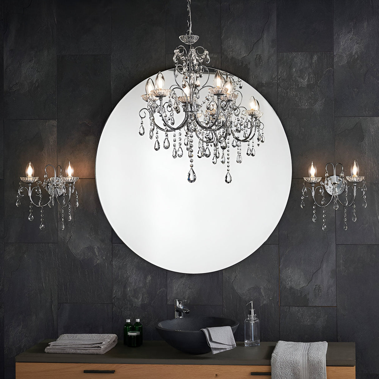 Endon Crandon 5 light bathroom chandelier in polished chrome with crystal droplets, reflected in a round mirror above a dark tiled vanity.
