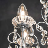 Close-up of Endon Crandon 5 light bathroom chandelier in polished chrome, showing a candle bulb, fluted glass cup, scrolled arms and clear crystal droplets.