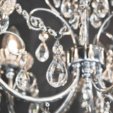 Close-up of the Endon Crandon bathroom chandelier showing polished chrome scrollwork, faceted crystal chain strands, and a clear teardrop crystal droplet.