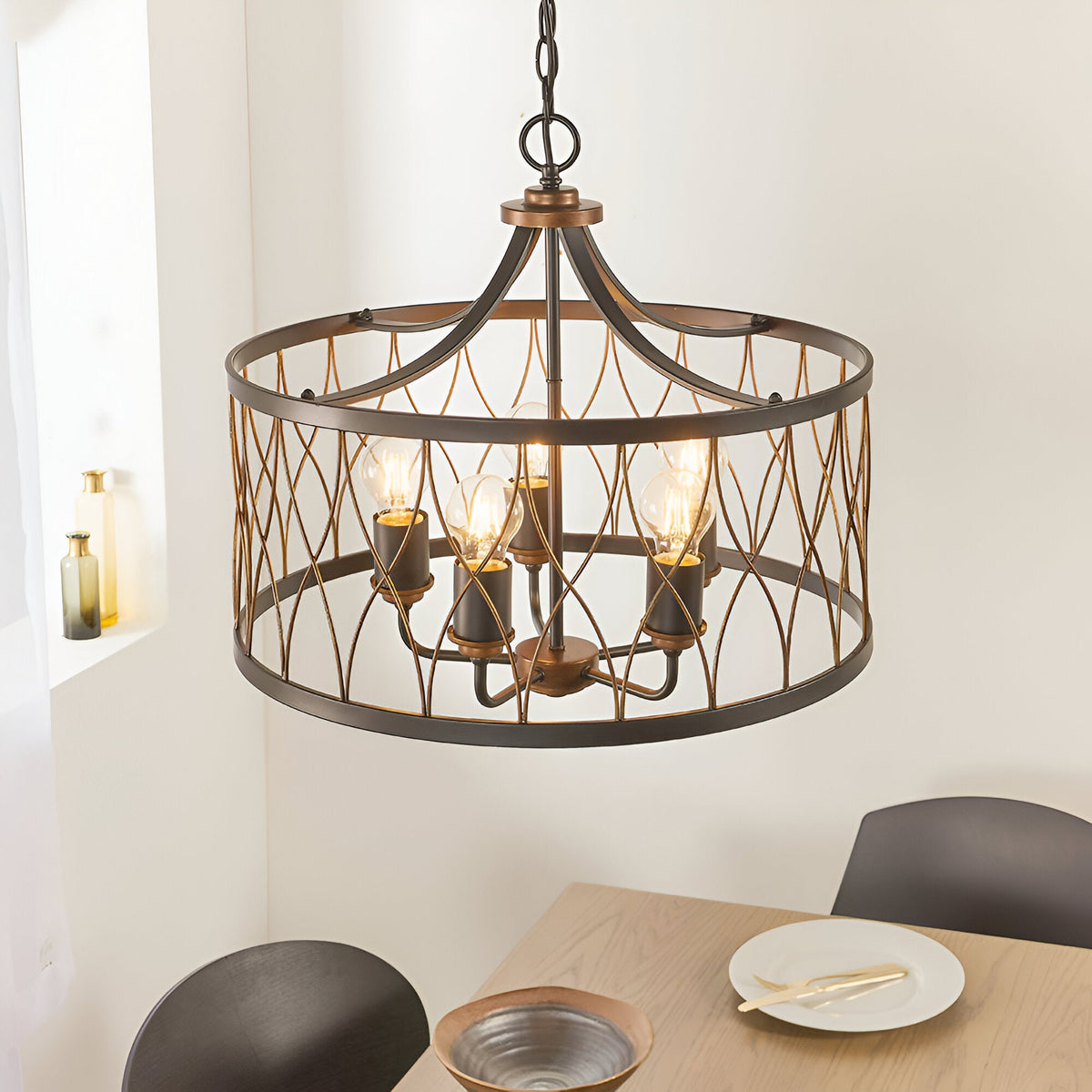 Hulton 5 Light Pendant in bronze and black with open lattice metalwork and five exposed bulbs, hung above a dining table on an adjustable chain.