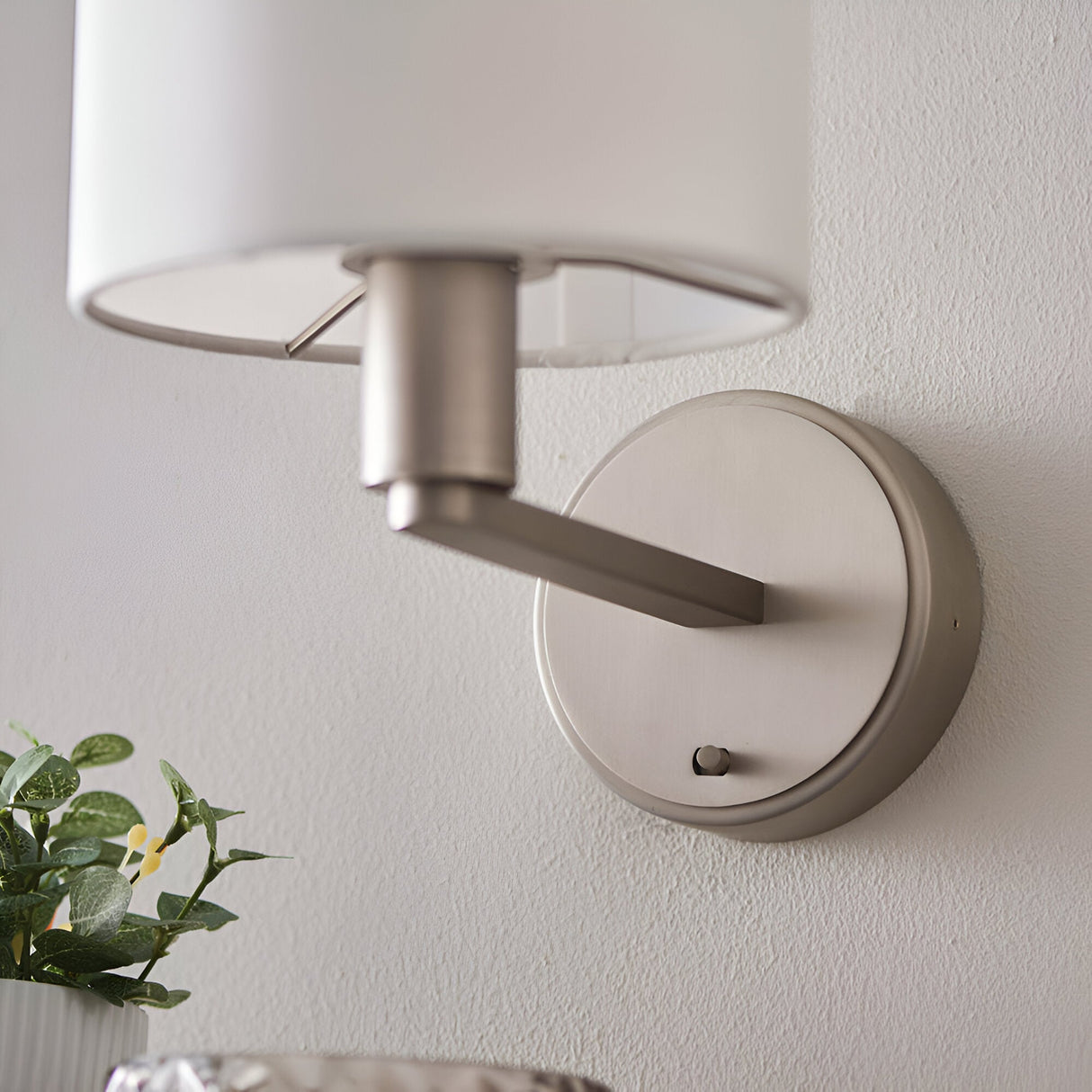 Bexley Wall Light in nickel with a white fabric shade, shown mounted on a wall with a switch on the round base and angled arm.