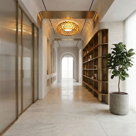 A modern hallway with light marble floors, gold-framed glass doors, a Briller LED Flush Ceiling Light – Gold, open shelves with decor, a potted plant, and tall windows dressed in sheer curtains.