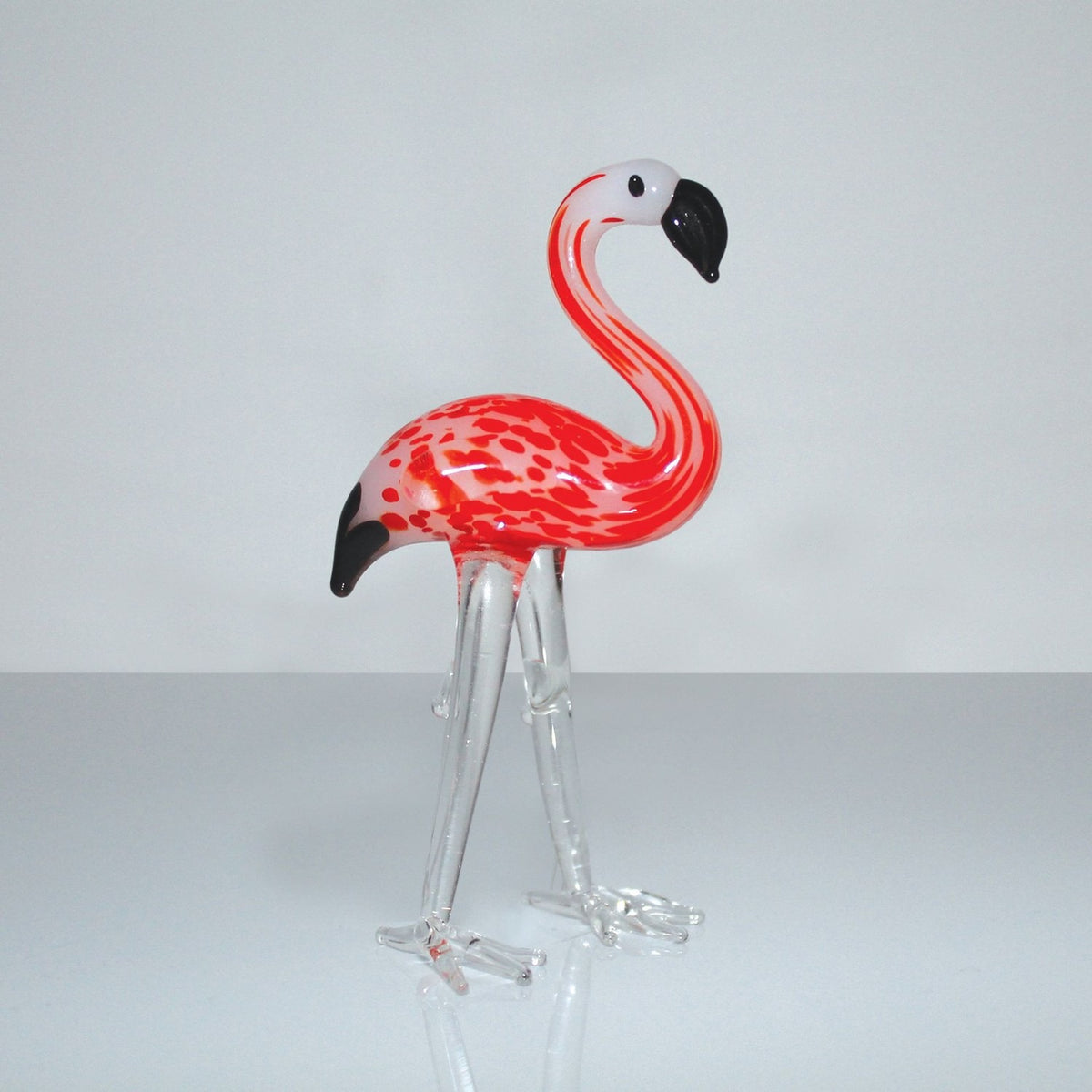 Standing Flamingo Miniature Glass Figurine in red and white, with a curved neck, black-tipped beak, clear glass legs and feet, set against a plain light background.