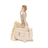Golden Gatsby Lady resin trinket box, a 1920s figure in a pale gold gown seated on a cream chest with a drawer, holding a fan, on a plain white background.
