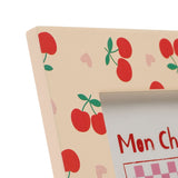 Close-up of the Cherries and Hearts Wooden Photo Frame in peach, showing the broad flat border with red cherries, green leaves and pink hearts against a white background.