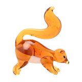 Miniature glass squirrel figurine in translucent orange with a white underside, tall curled tail, small ears and dark eyes, shown on a plain white background.