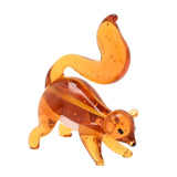 Miniature glass squirrel figurine in warm orange with a white underside, tall curled tail, small ears and dark eyes, bubbles visible in the glass, on a plain white background.