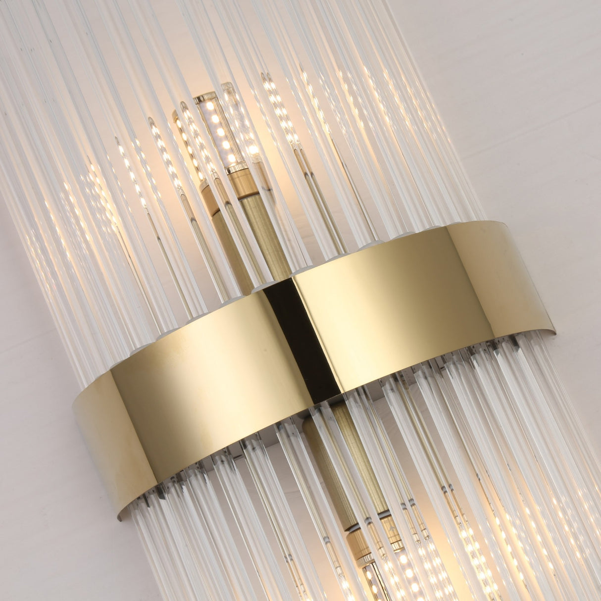 The Oriana 2 Light Crystal Wall Light - Gold features vertical glass rods, a central gold metallic band, and LED rows, creating a sleek, luxurious look that adds contemporary elegance to any space.