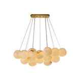 The Noctis 9 Light Small Floating Globes Alabaster Chandelier in brushed brass features a modern rectangular base and multiple alabaster glass globes suspended at varying lengths, creating an elegant cluster of glowing spheres.