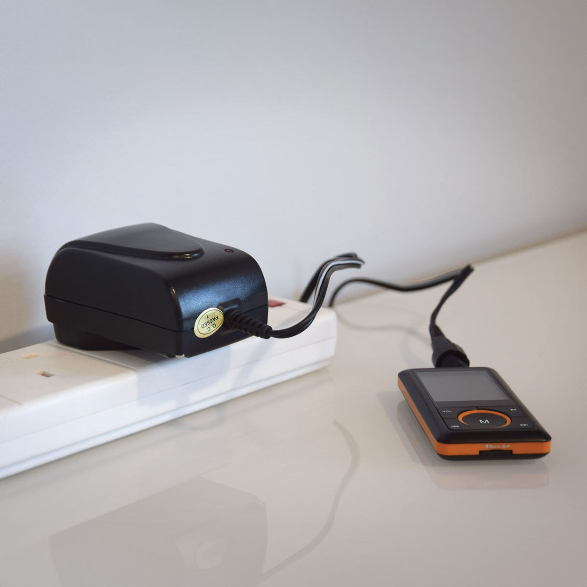 Mercury SMDC400UK switch-mode 12V power supply by AVSL plugged into a white extension socket, powering a small orange and black media player.