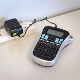 Mercury SMDC401UK 12W switch-mode power supply by AVSL plugged into a white UK extension lead beside a label maker on a light worktop.