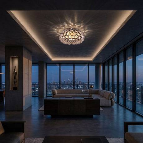 Modern living room with floor-to-ceiling windows at dusk, a large beige sofa, dark furnishings, and a decorative chandelier featuring the Briller LED Flush Ceiling Light - Transparent with patterned lighting on a recessed ceiling.