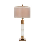 The Alverin 1 Light Segmented Alabaster Table Lamp in brass & soft white features a cylindrical beige shade, gold and white column base, and a square gold stand, displayed against a white background.