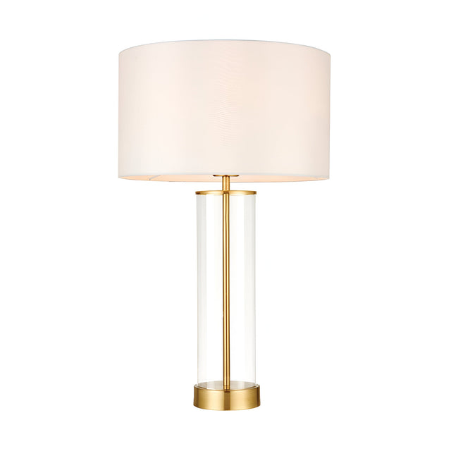 Endon Caldley table lamp with clear cylindrical glass base, satin brass fittings and vintage white faux silk drum shade, on a plain white background.