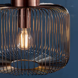Castdale Cage Pendant in antique copper finish, close-up of open wire cage shade with visible E27 bulb, set against a dark blue background.
