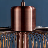 Castdale Cage Pendant in antique copper, close-up of the cylindrical metal fitting with wire cage frame, on black flex against a dark blue background.