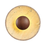The Torello LED Round Travertine Wall Light features a walnut brown and light beige design, with a textured outer ring and smooth central sphere, casting a warm glow from behind the sphere.