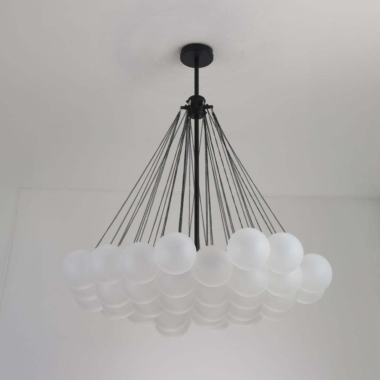 Niori Orb 37 Light Cluster Chandelier in black with frosted glass globes suspended on fine chains from a matt black ceiling rose and rod.