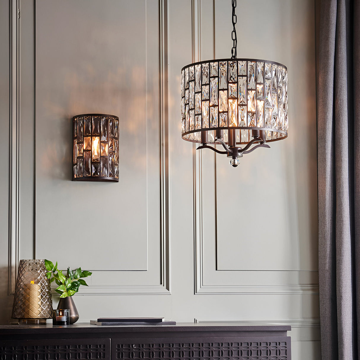 Endon Aldwick 5 light pendant in dark bronze with tiered faceted crystals, shown lit beside a matching crystal wall light in a panelled room.