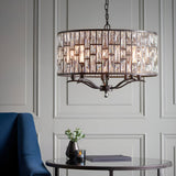 Endon Aldwick 8 light pendant in dark bronze with tiered faceted crystal drum shade, hung above a mirrored side table in a panelled living room.