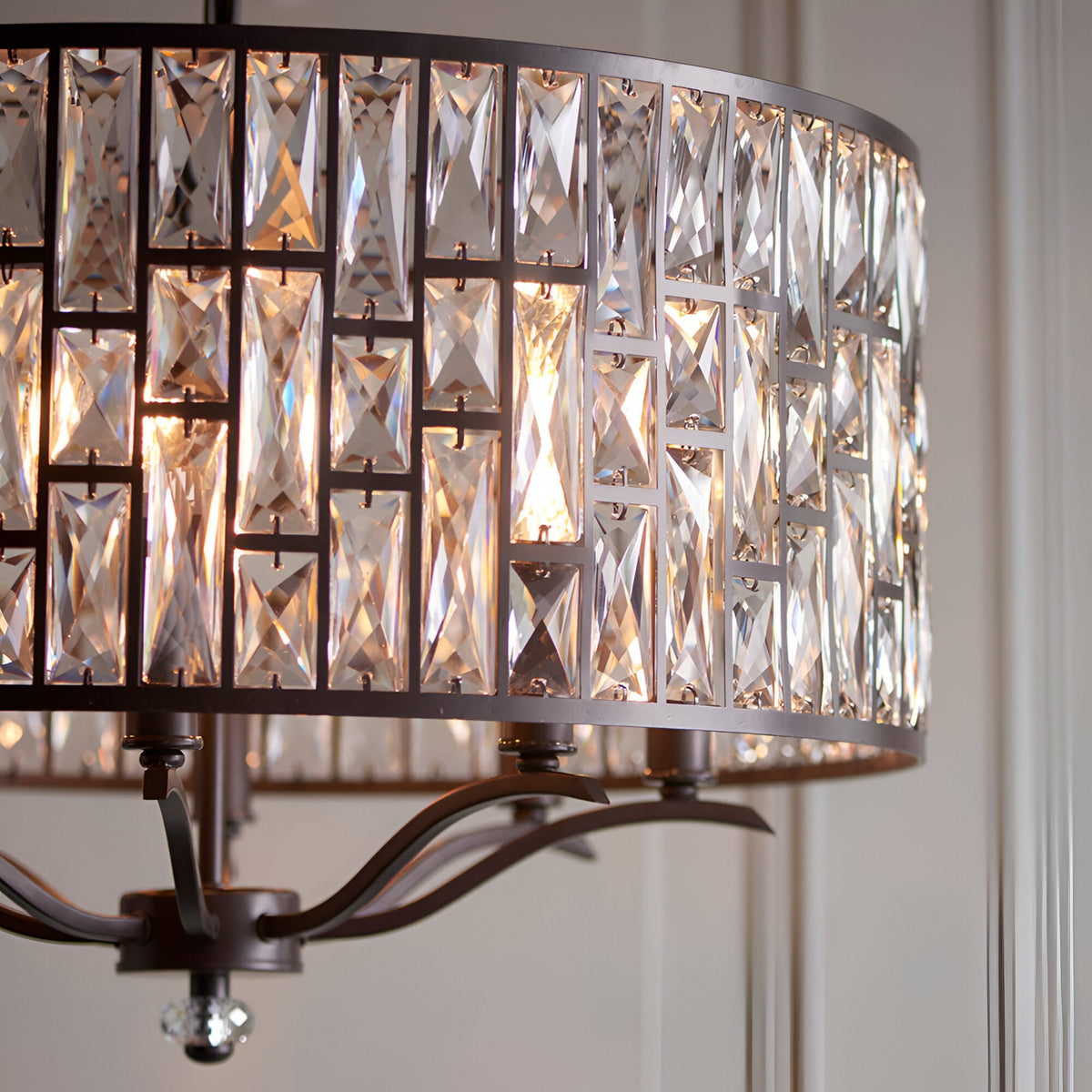 Close-up of the Endon Aldwick 8 Light Pendant in dark bronze, showing tiered faceted K5 crystal drum shade illuminated with warm light.