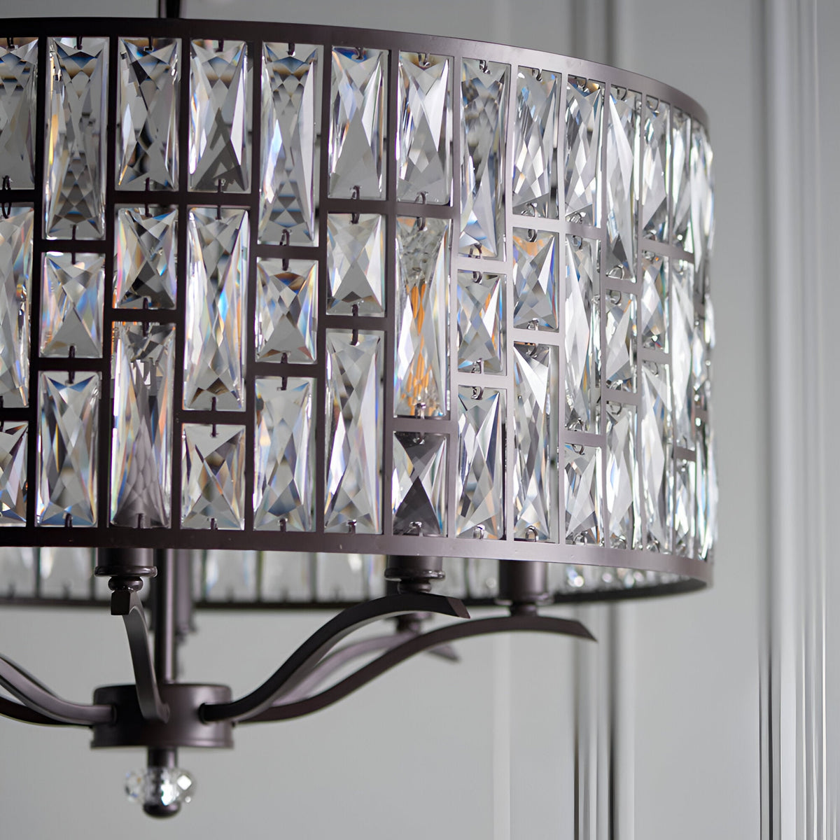 Close-up of Endon Aldwick 8 Light Pendant in dark bronze, showing tiered faceted K5 crystal drum shade and curved arms against a pale panelled wall.