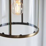 Close-up of the Caldbury Pendant Light in brass, showing its clear glass panels, slim metal frame, and exposed E27 filament bulb.