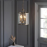 Caldbury 4 Light Pendant in brass with clear glass panels and candle lamps, hanging from a chain in a dark-panelled hallway.