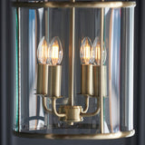 Caldbury 4 Light Pendant in brass, close-up of candle-style E14 bulbs on brass arms within a clear glass panel enclosure.