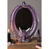 Oval resin mirror with purple metallic finish and silver-highlighted scales, featuring a dragon perched at the base with wings curving up to meet at the top, displayed with candles and crystals.