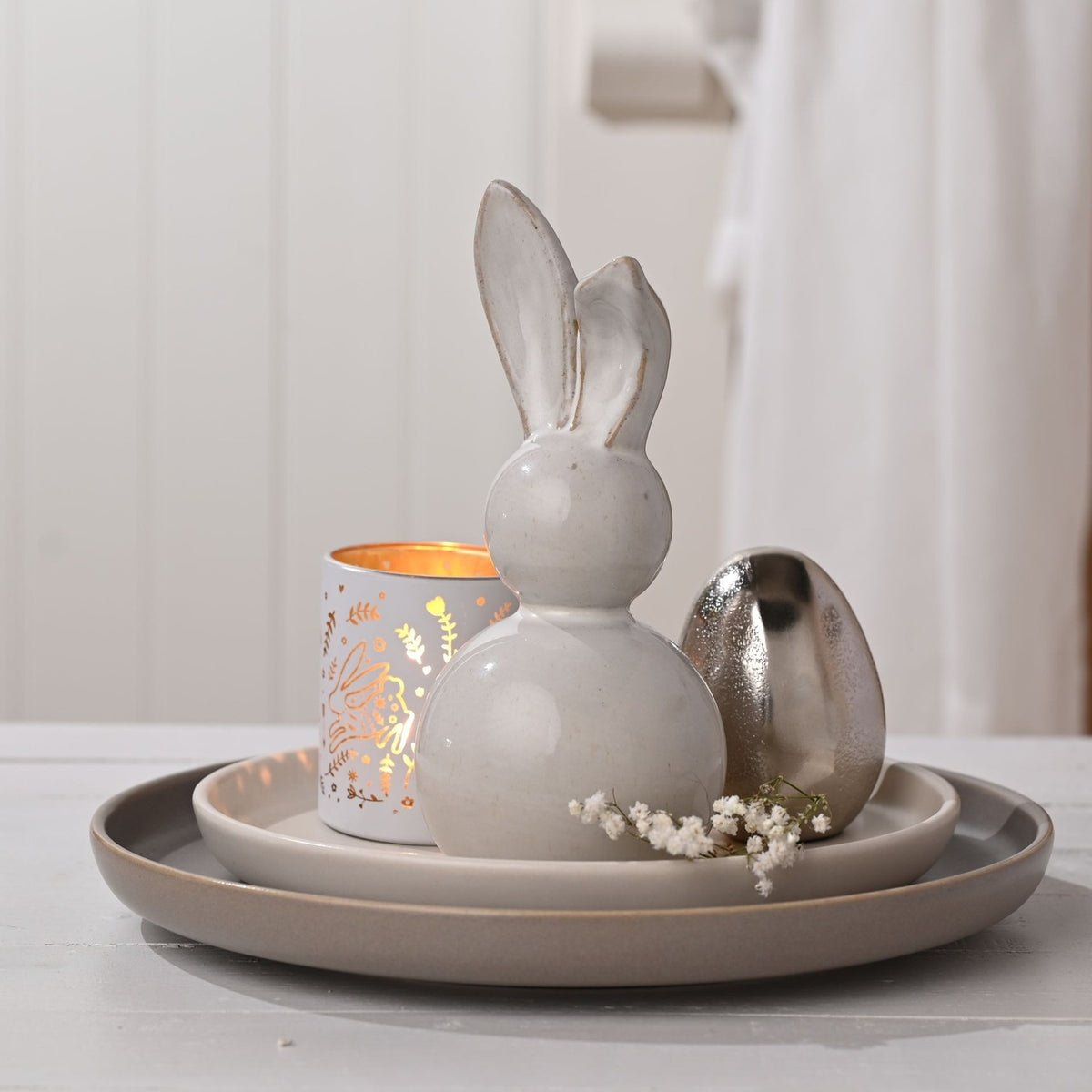 Ceramic bunny decoration, 19.6cm, with rounded body and tall floppy ears in white and grey glaze, displayed on a plate with a gold-detailed tea light holder and silver egg.