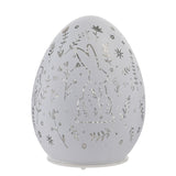 White glass Easter egg LED light-up decoration with cut-out rabbit, flower, leaf, and star patterns, standing on a small round base against a plain white background.