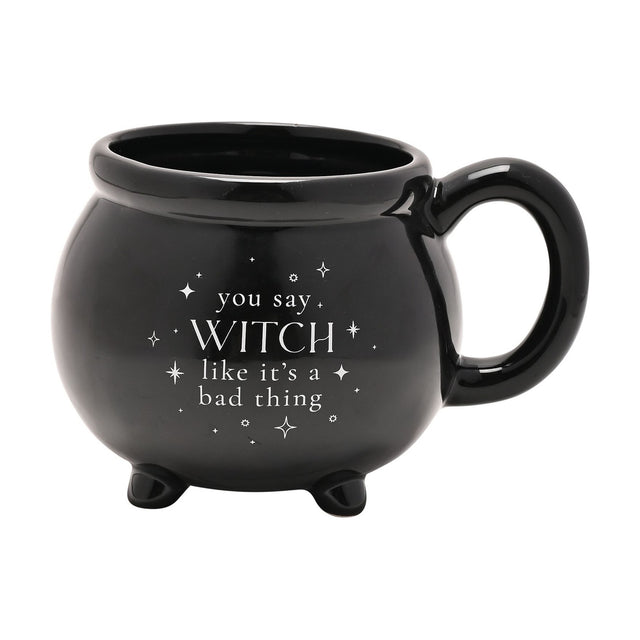Black ceramic cauldron mug with stubby feet and loop handle, glossy finish with white "you say WITCH like it's a bad thing" text and stars, on a plain white background.