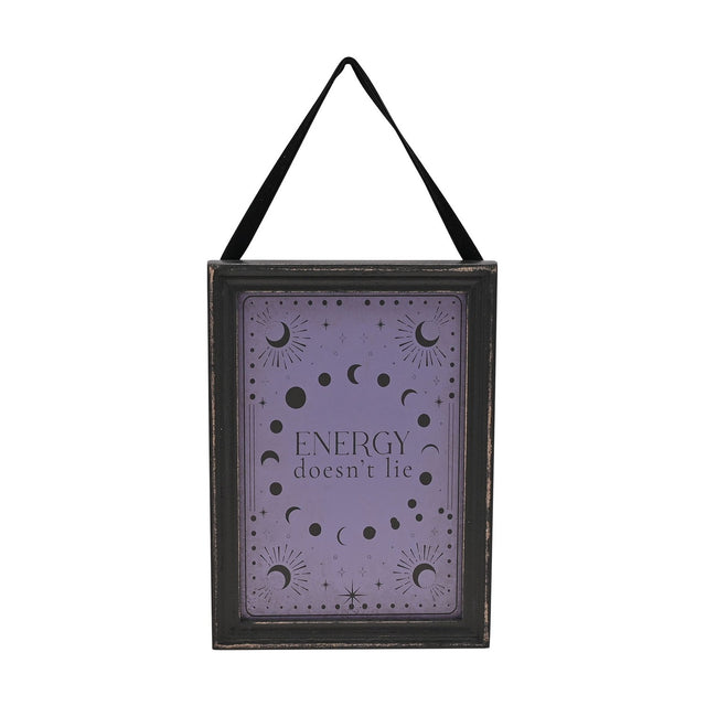 Wooden hanging wall plaque with black frame and black ribbon, featuring a purple face with moon phases, crescent moons, stars, and the text "Energy doesn't lie," shown on a white background.