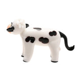 Standing Black Spotted Cow Glass Miniature Figurine in milky white glass with black spots, peach muzzle, curled white forelock, and black curved tail, shown on a plain white background.