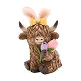 Sitting Highland Cow Easter Bunny resin decoration in brown, wearing white bunny ears with a yellow bow and holding lilac and pink tulips, shown on a plain white background.